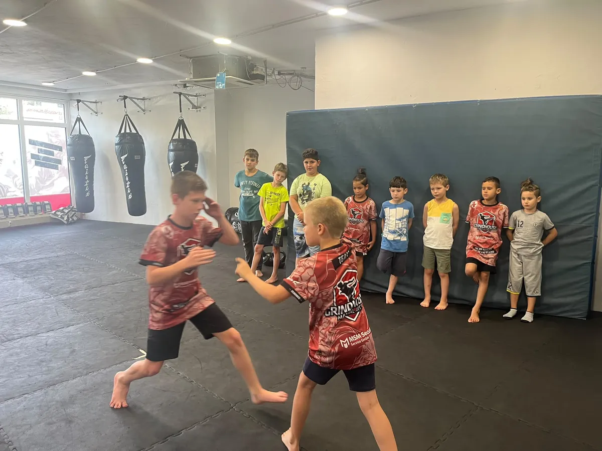 Zwei Kinder sparren im Kickboxen-Kurs, die Gruppe schaut zu