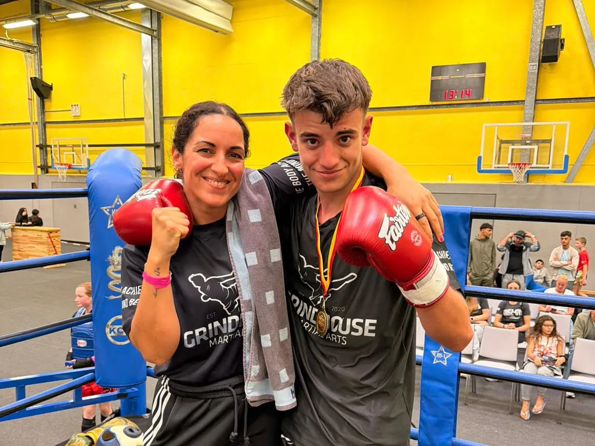 Trainerin und Jugendlicher mit Medaille nach dem Kickbox-Wettkampf